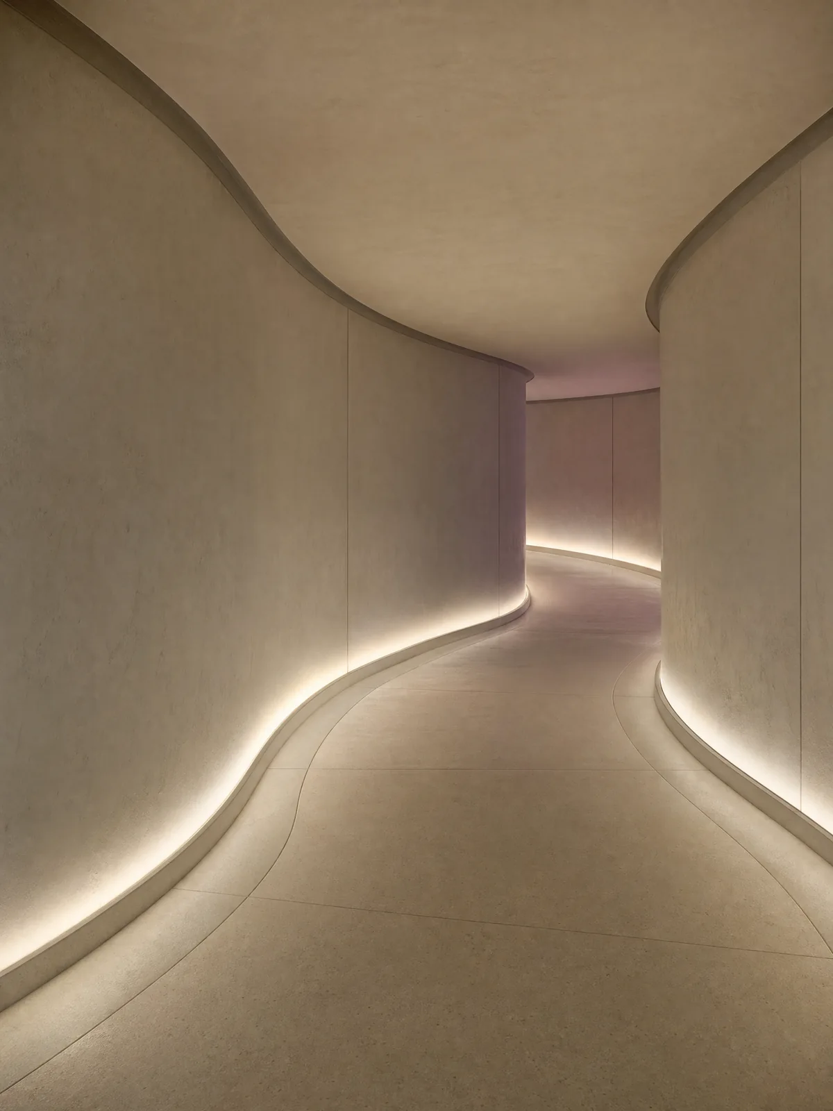A warm institutional white hallway following a gentle S-curve with no visible doors